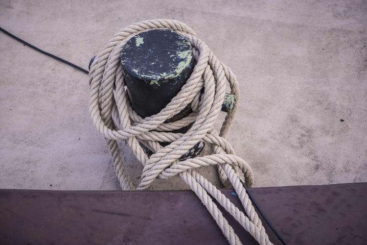 High angle view of rope tied on bollard at harbor