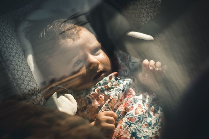 High angle of cute baby lying on car seat