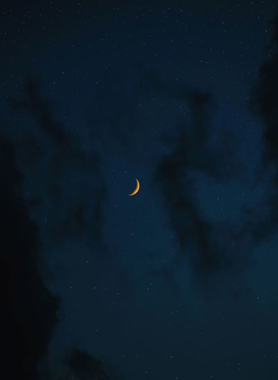 Low angle view of moon and stars  against sky at night