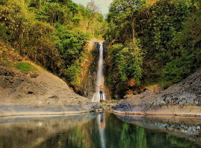 Rear view of man standing against waterfall