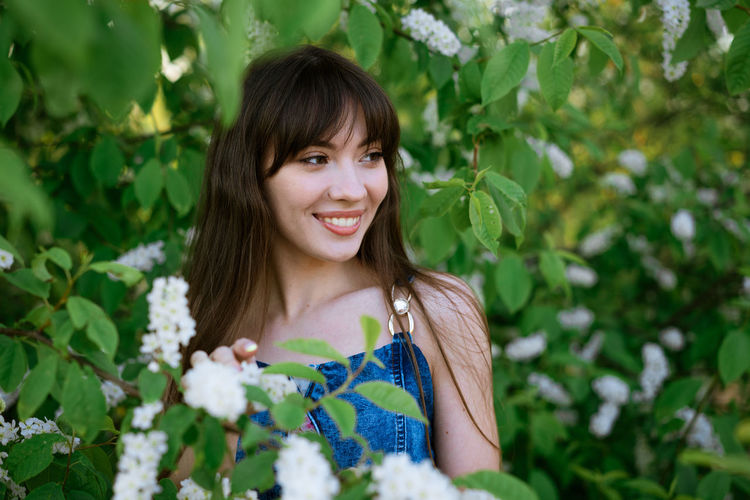 Portrait of a beautiful young woman on the background of a flowering bush