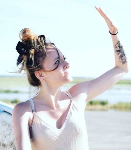 Portrait of young woman with arms raised standing at beach