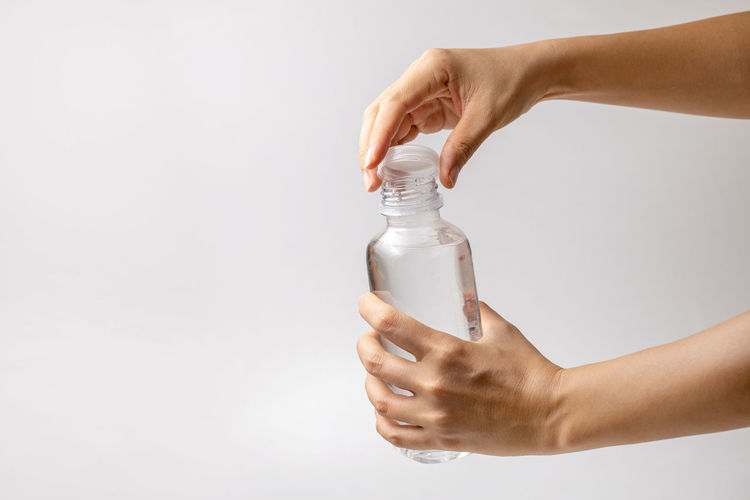 Close-up of woman hand holding bottle against white background