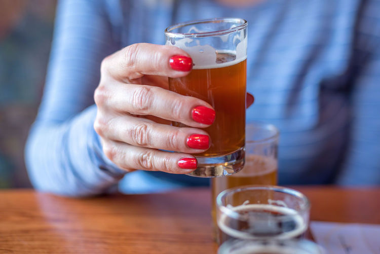 Close-up of woman holding glass of beer from flight at brewery