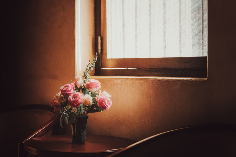 Flower vase on table by window