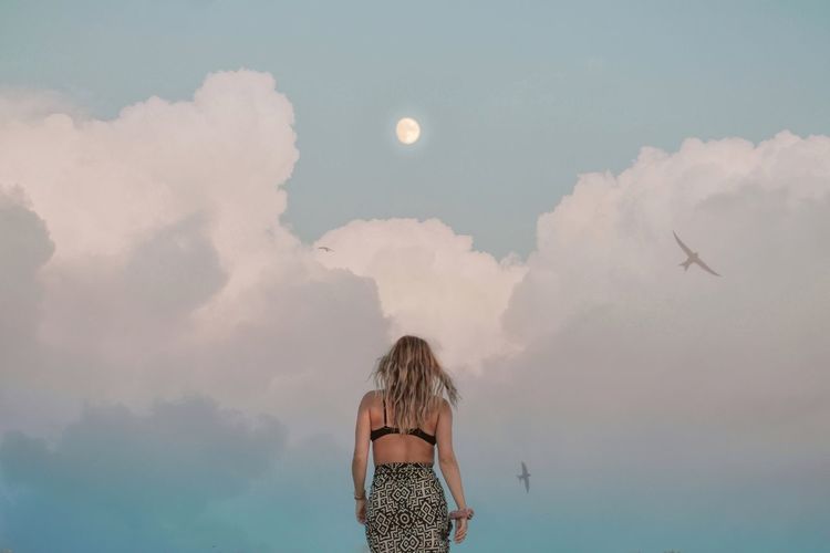 REAR VIEW OF WOMAN STANDING IN THE SKY