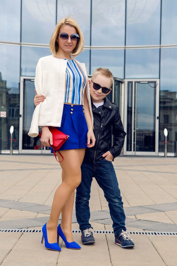 Young business woman in short blue trunks standing and waiting for  the bank of glass and her son