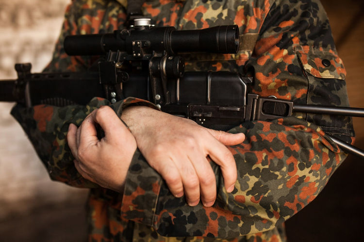The soldier is holding the gun in his hands