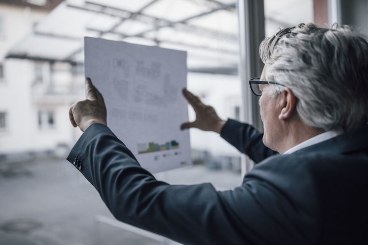 Senior businessman looking at paper at the window