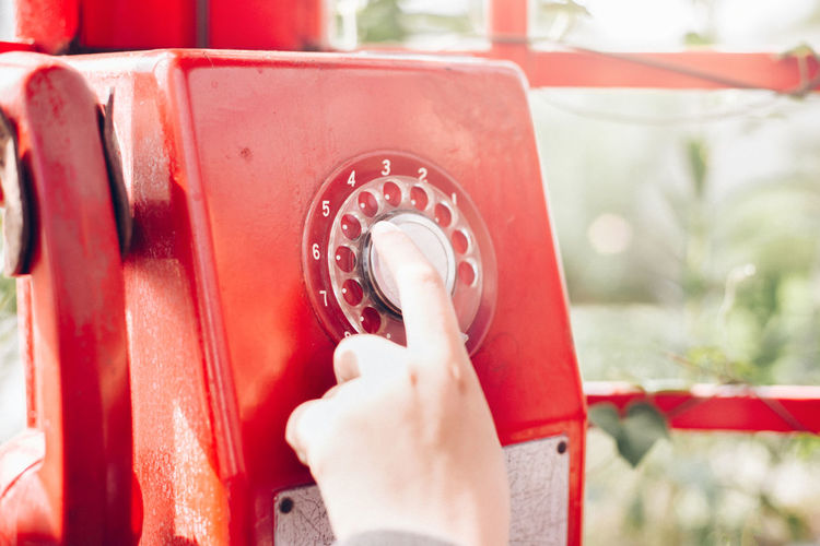 Close-up of human hand operating old rotary payphone