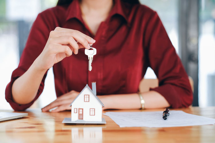 Midsection of businesswoman holding house key at desk