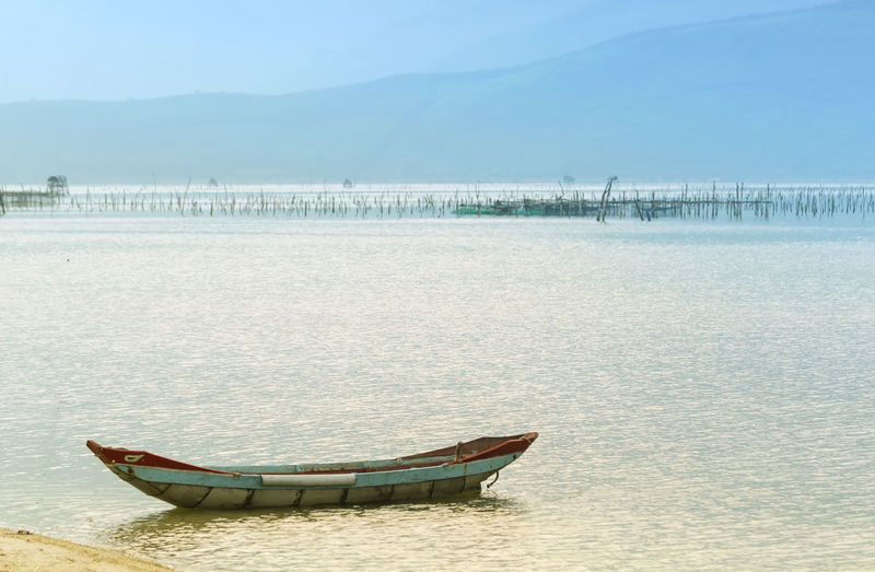 Boat moored on beach against sky