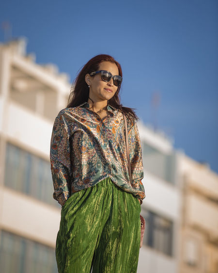 Portrait of young woman standing against buildings