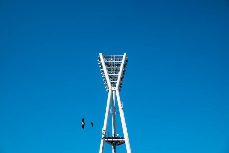 Low angle view of floodlight against clear blue sky
