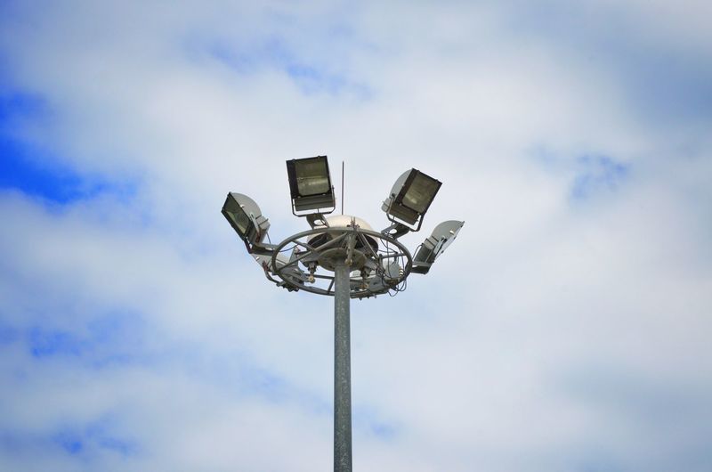 Low angle view of floodlight against cloudy sky