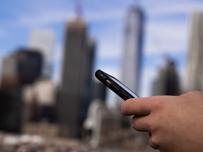 Close-up of person using mobile phone against sky