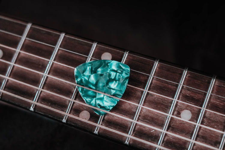 Close-up of guitar with pick against black background