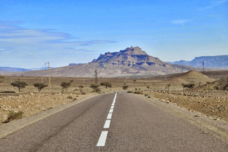 Road leading towards mountains against sky