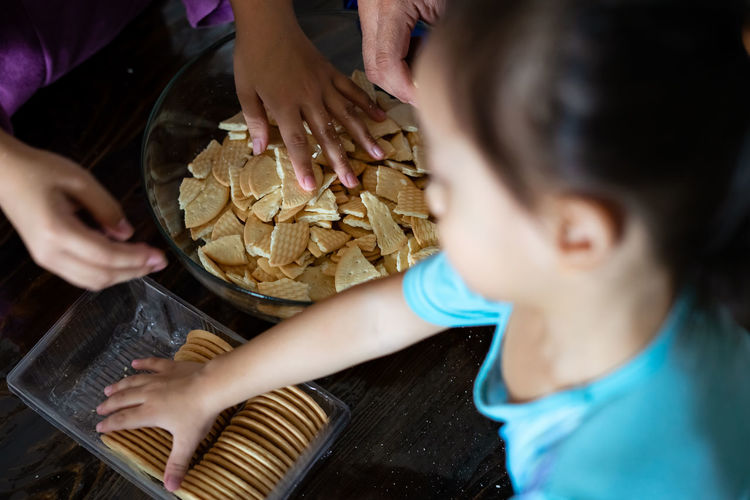 Kids making kek batik or malaysian triple chocolate dessert. crushing the cookies into tiny pieces