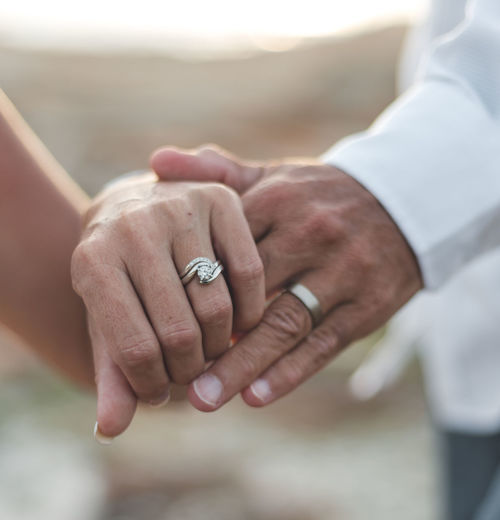 Close-up of couple showing wedding rings
