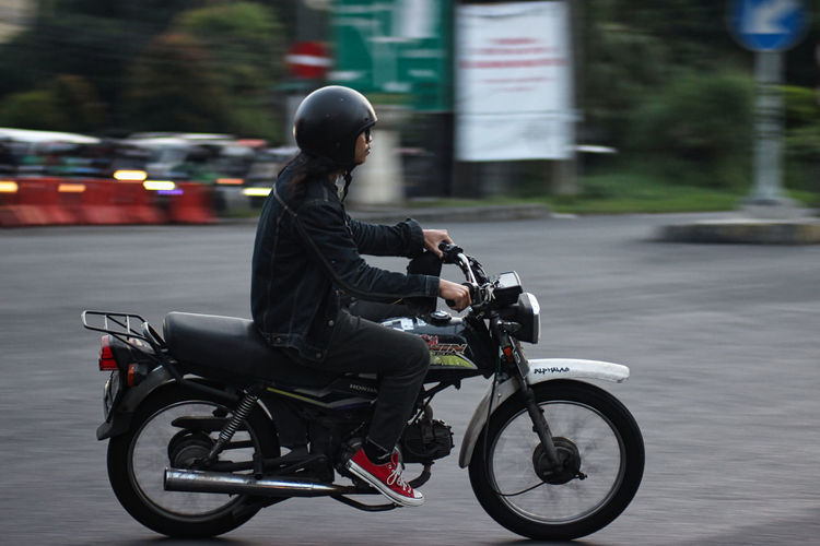 Side view of man riding motorcycle on street