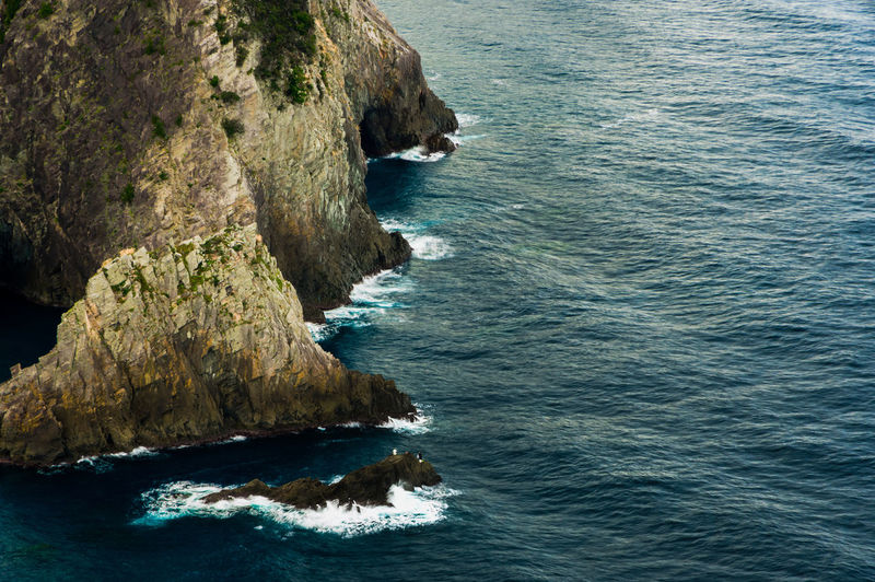 Telephoto shot of waves lapping a sea stack along the kumomi coastline.