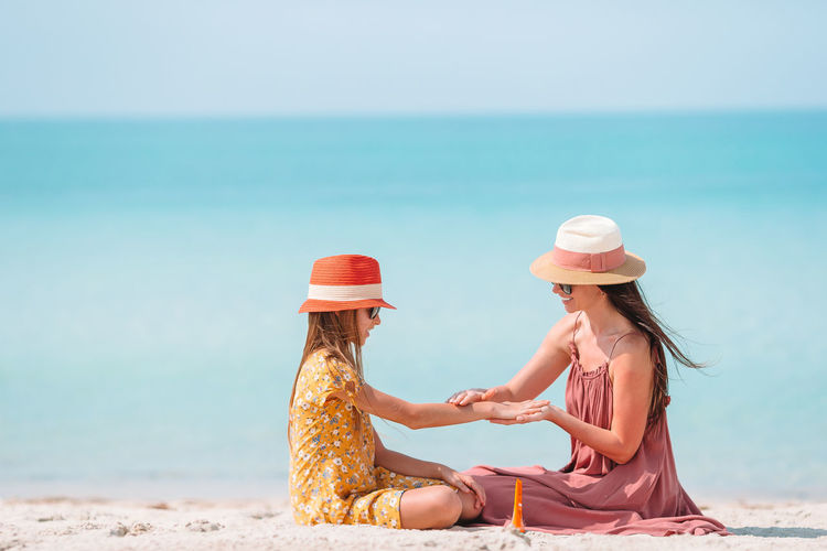 Mother applying sunscreen to daughter at beach