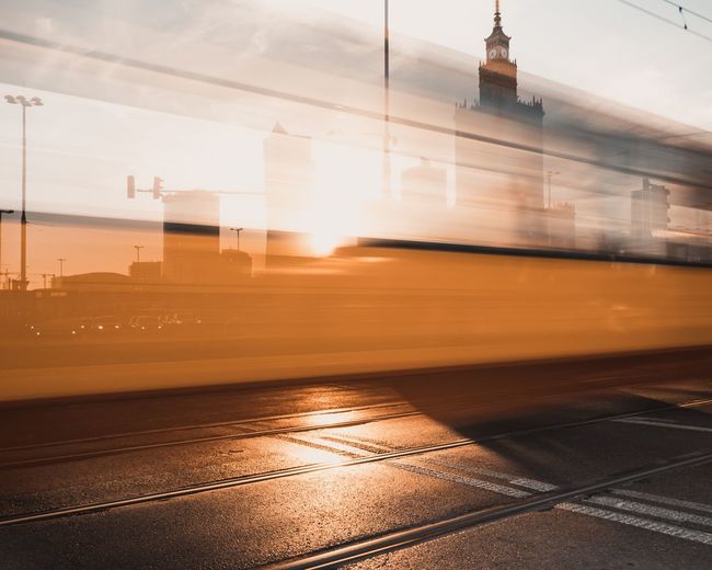 Blurred motion of tram on road in city during sunset