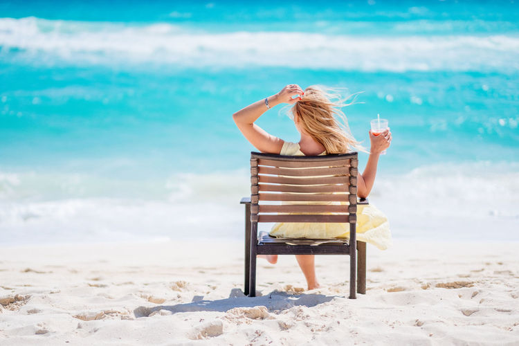 Woman sitting on beach against sea