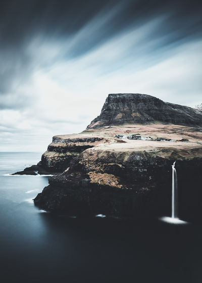Scenic view of sea by mountains against sky