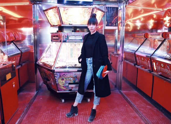 Portrait of woman standing by arcade game at amusement park