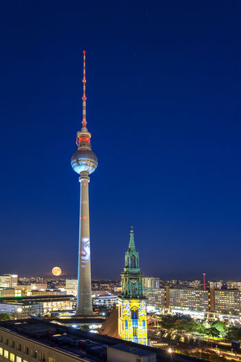 Illuminated tower against clear blue sky at night