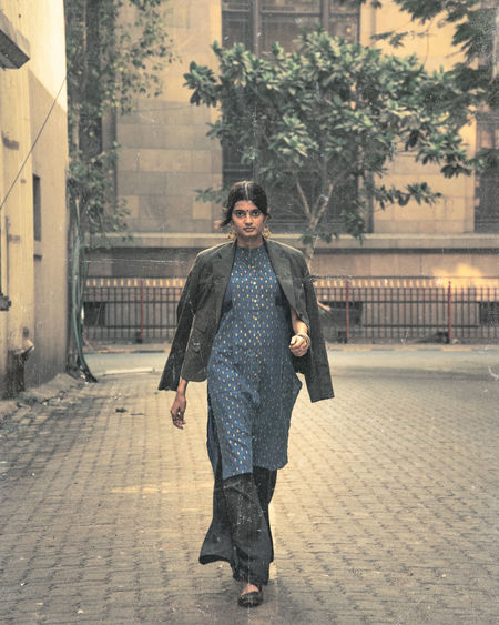 Full length portrait of model woman walking on street in city