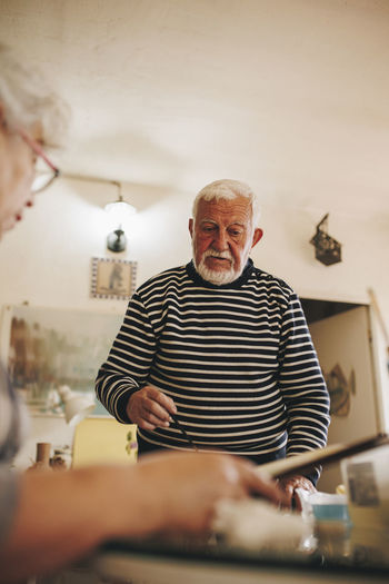 Senior man talking with artist at home