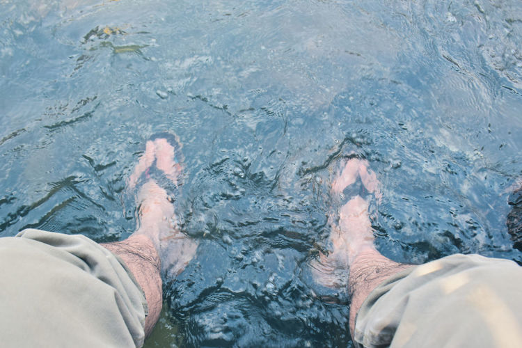 Low section of man relaxing in swimming pool