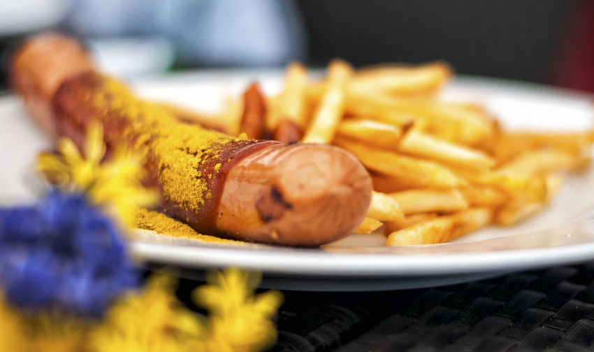 Close-up of sausage and french fries in plate on table