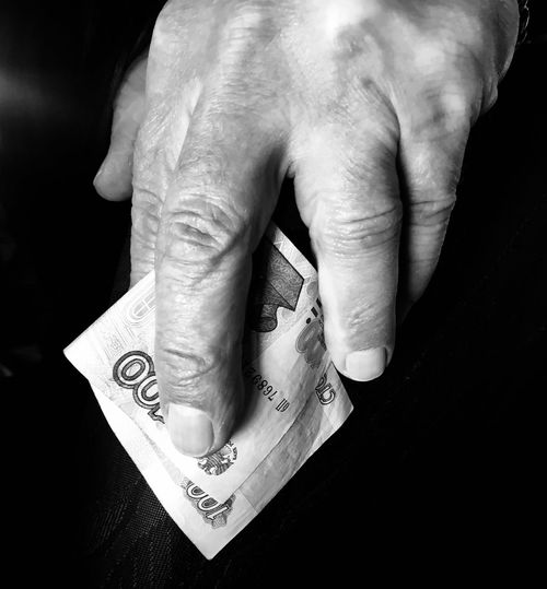 Close-up of human hand holding hat against black background
