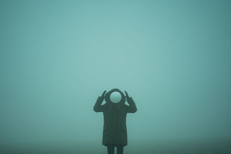 Person with balloon standing in foggy weather
