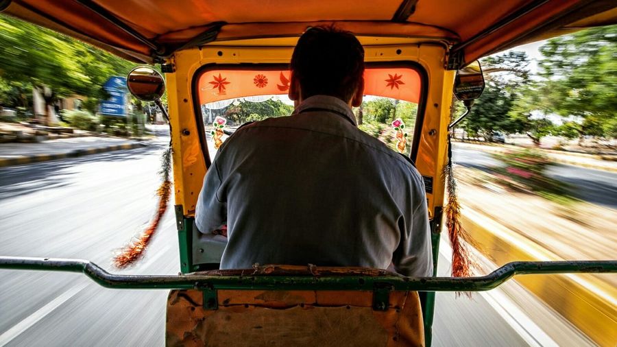 Rear view of man riding auto rickshaw