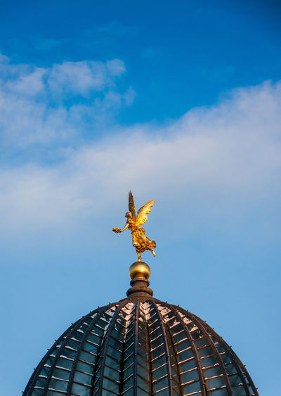 Golden angel statue on dome against sky