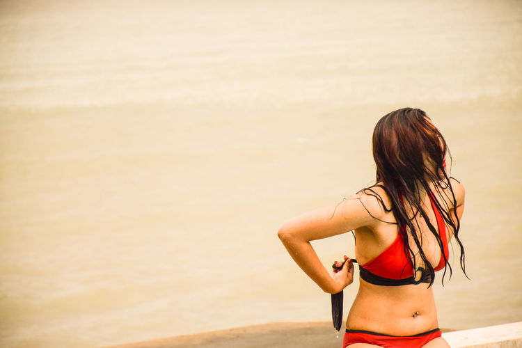Woman tying bikini top at beach