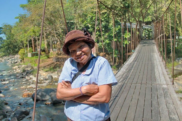 Portrait of smiling senior woman standing on footbridge
