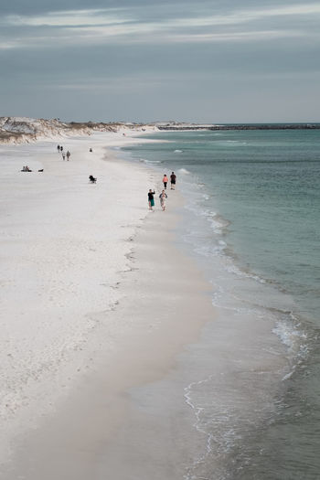 People walking the water's edge on the white sandy beaches of panama city, florida