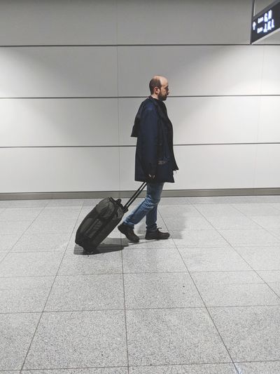 Full length of man with luggage walking at airport