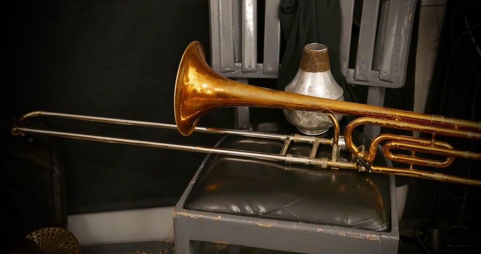Close-up of trombone and container on chair at home