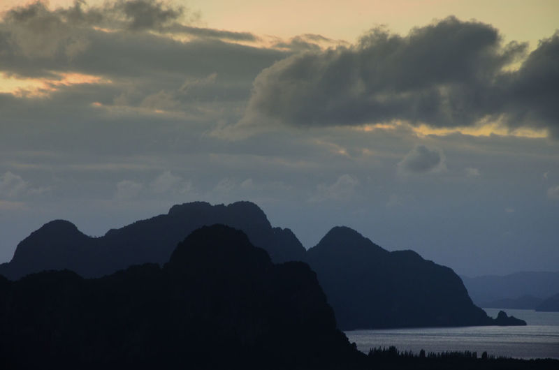 Silhouette mountain by sea against sky at sunset