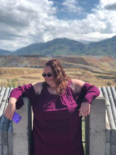Overweight woman wearing sunglasses standing against mountains