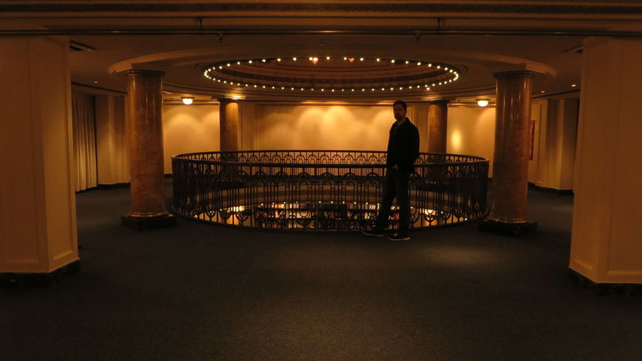 Rear view of man standing in illuminated room