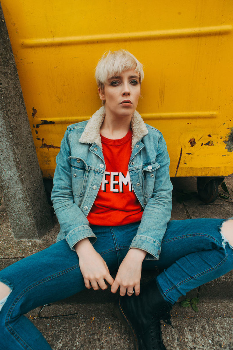 one person, sitting, casual clothing, front view, real people, leisure activity, lifestyles, child, looking, boys, day, looking away, yellow, portrait, young adult, childhood, wall - building feature, males, contemplation, outdoors, beautiful woman, teenager