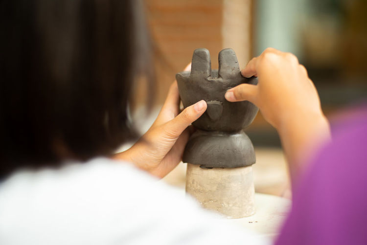 Rear view of girl making sculpture at workshop